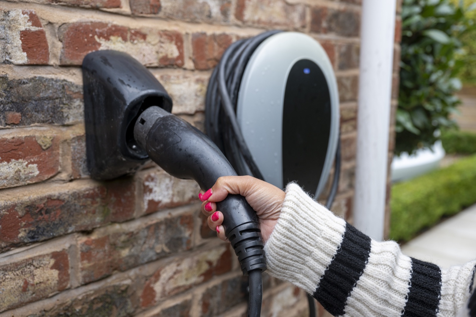 Homeowner plugging a charging connector into a wall-mounted home EV charge point in the Baltimore area