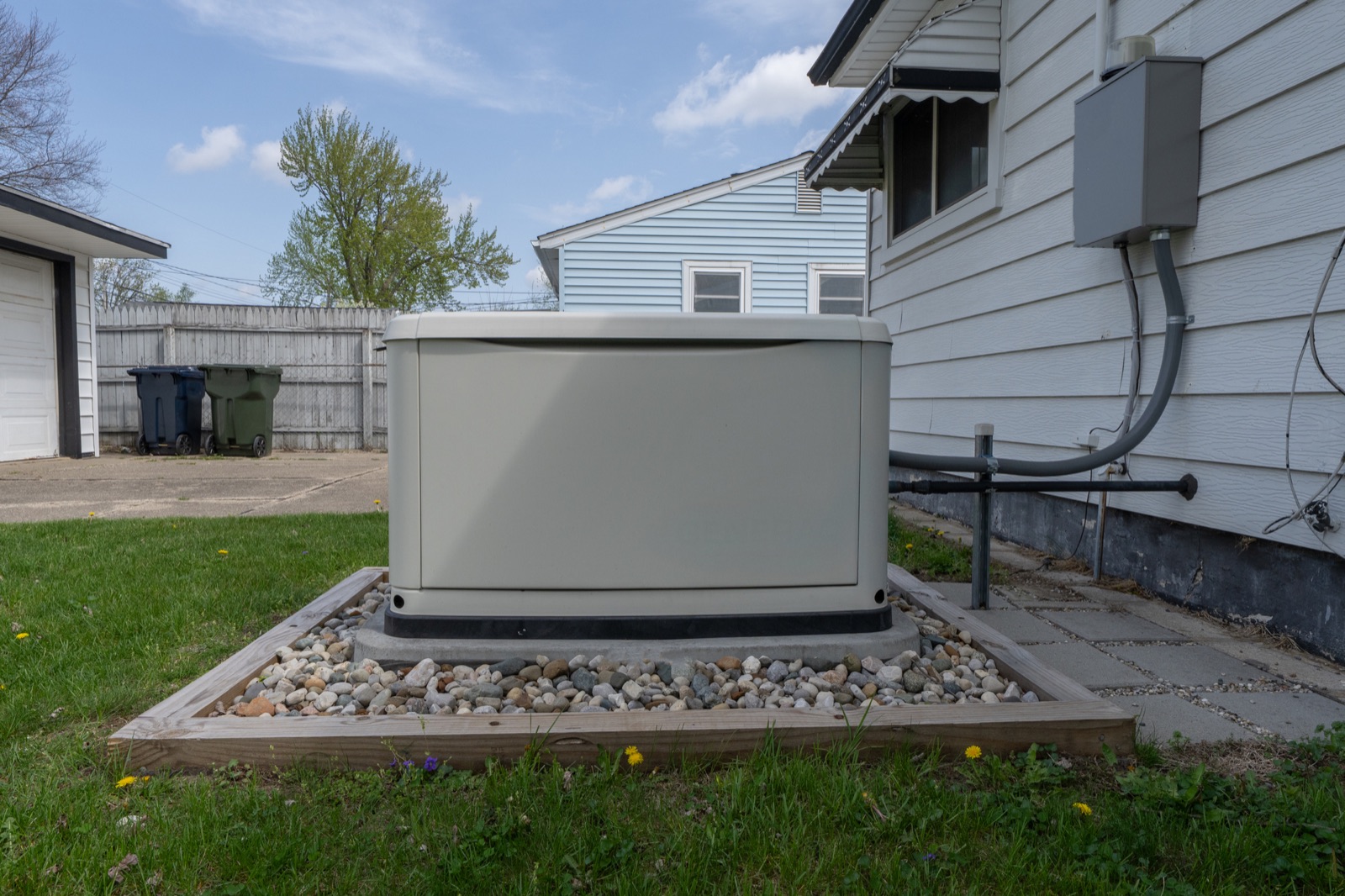 Whole-house standby generator installed on a gravel pad beside a Baltimore area home